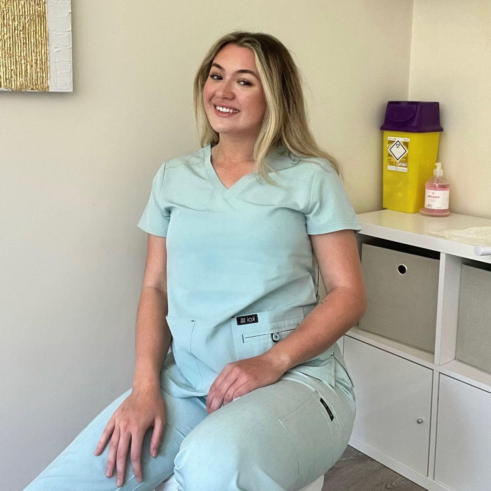 Femme kinésithérapeute en tenue médicale bleu clair assise sur une chaise