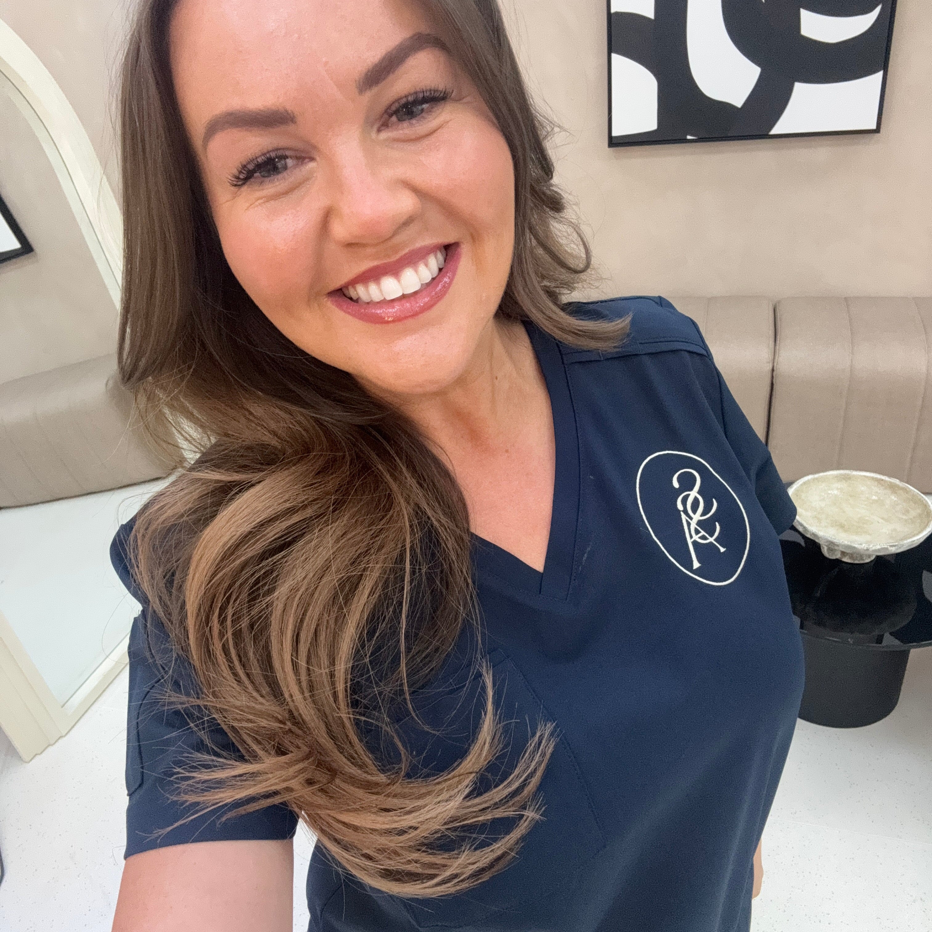 Professionnelle du médical portant une blouse Bleu marine avec un logo blanc brodé