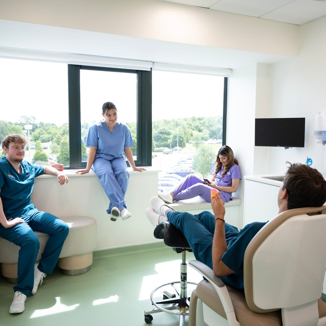 Groupe de professionnels de santé en tenue médicale discutant et se détendant dans une salle lumineuse d'un cabinet médical