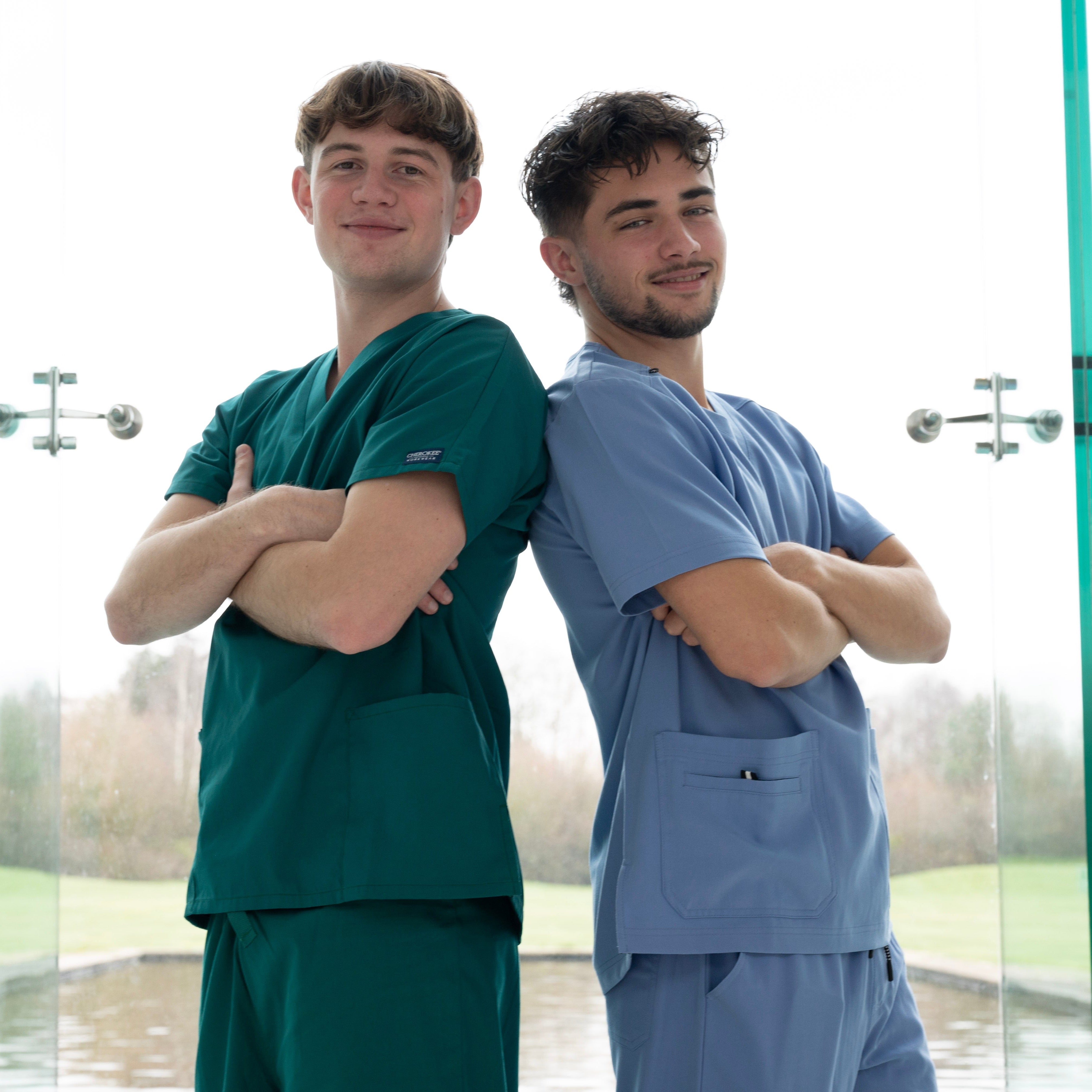 Deux aides-soignants dos à dos en tenues vert forêt et bleu ciel.