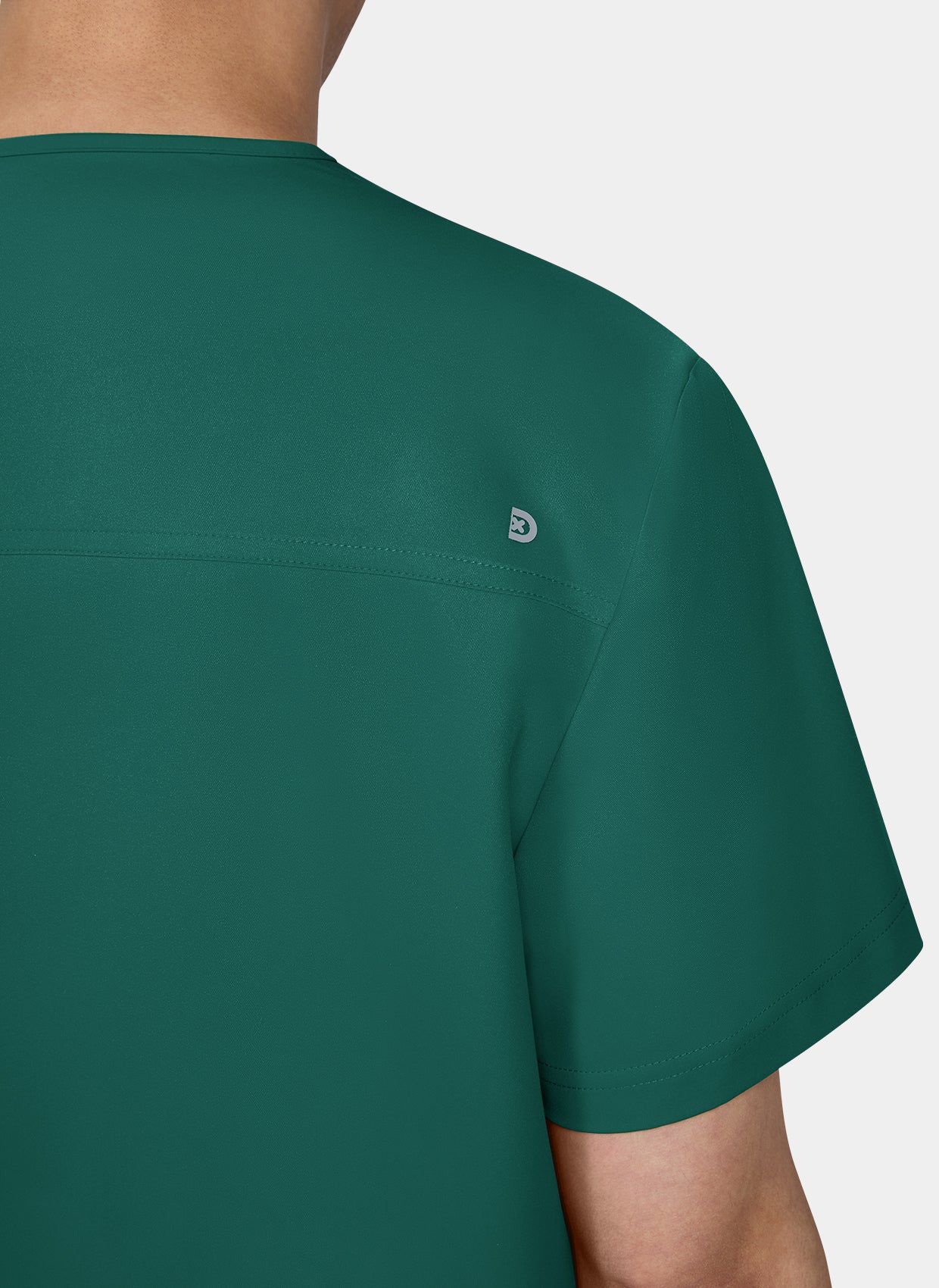 Zoom sur l'epaule d'un homme portant une blouse medicale koi cureology stasis vert foret