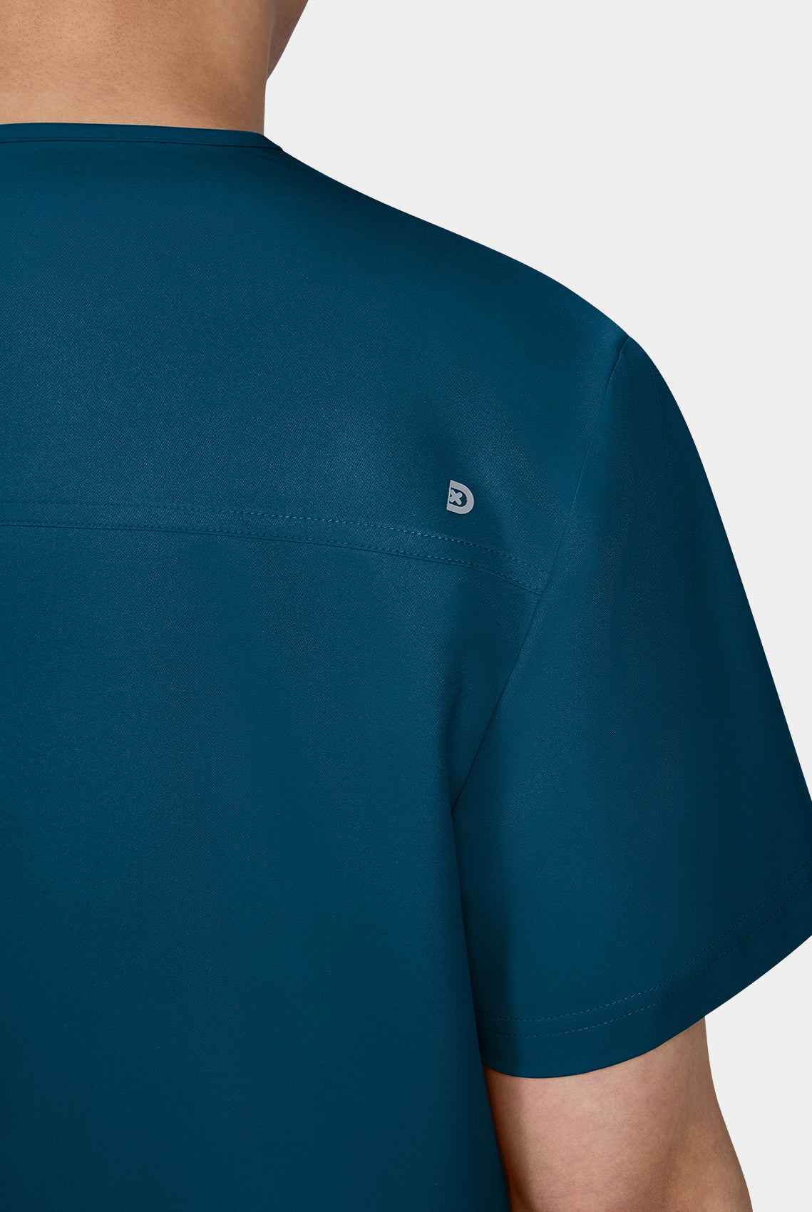 Zoom sur l'epaule d'un homme portant une blouse medicale Koi Cureology Stasis Bleu Caraibe