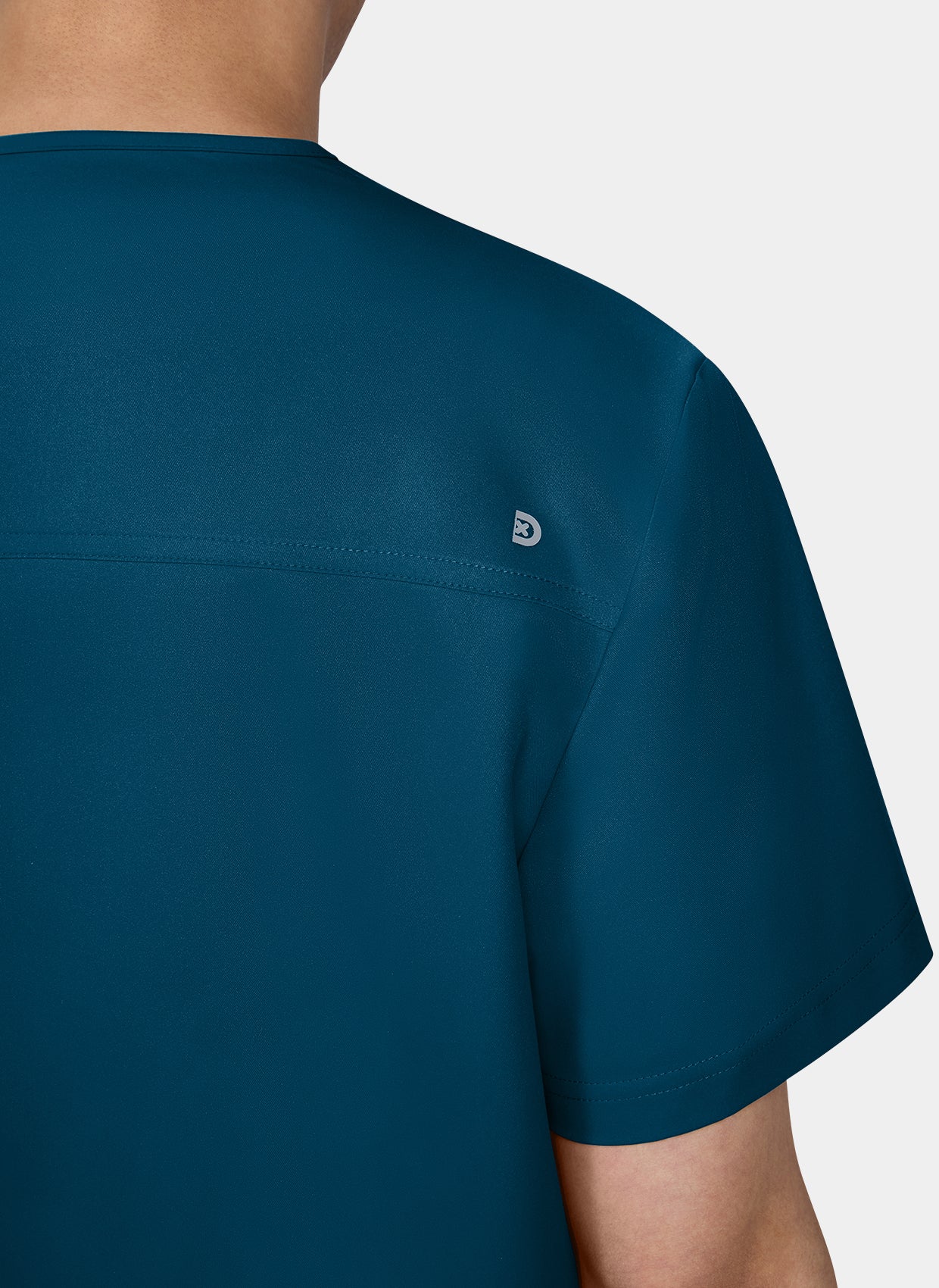 Zoom sur l'epaule d'un homme portant une blouse medicale Koi Cureology Stasis Bleu Caraibe