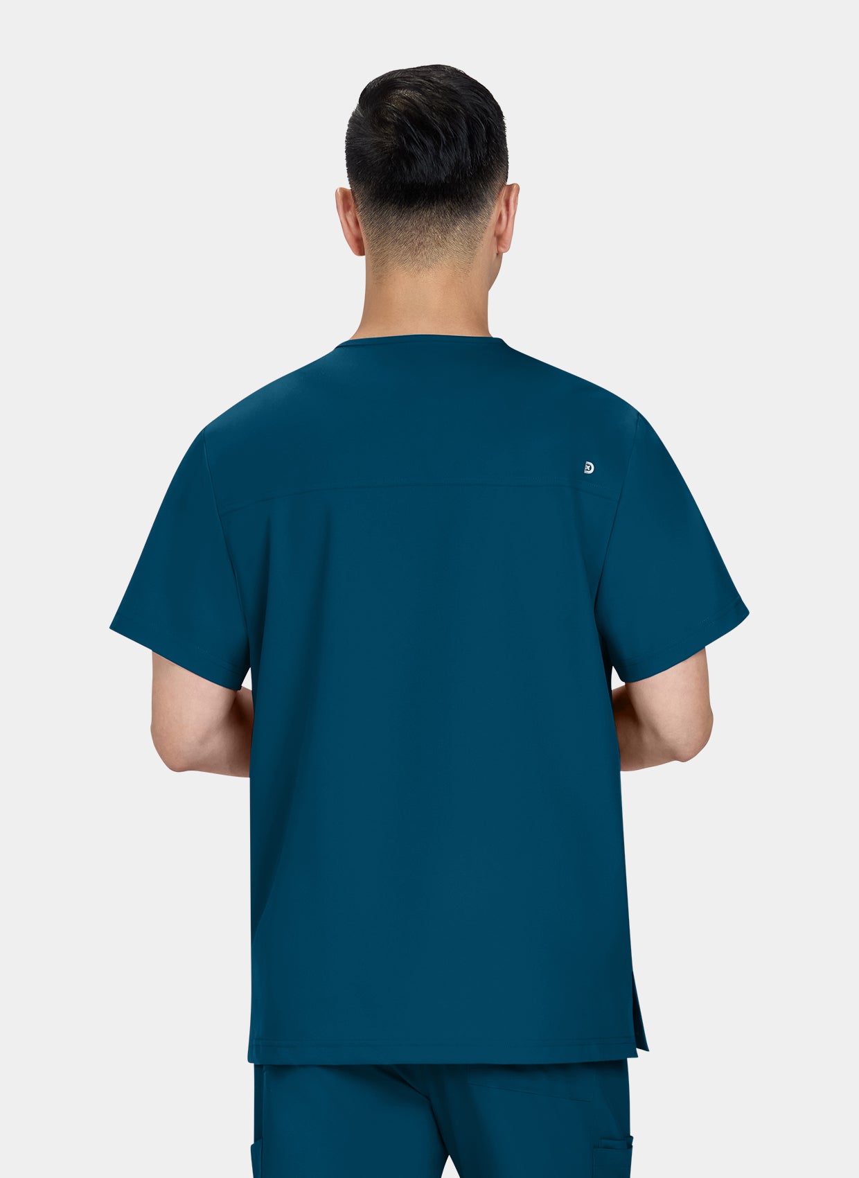 Homme de dos portant une blouse medicale Koi Cureology Stasis Bleu Caraibe