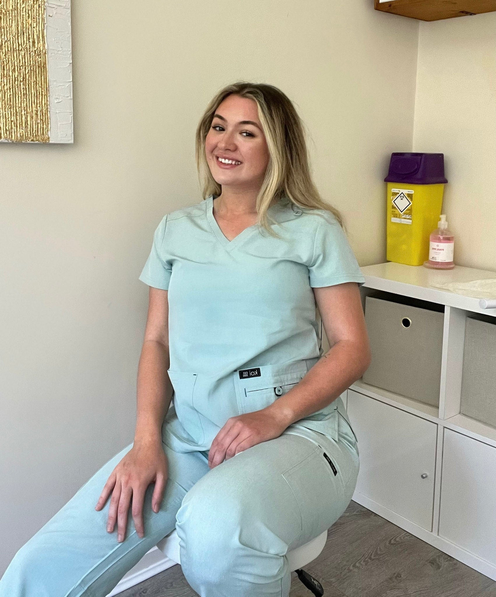 Femme kinésithérapeute en tenue médicale bleu clair assise sur une chaise
