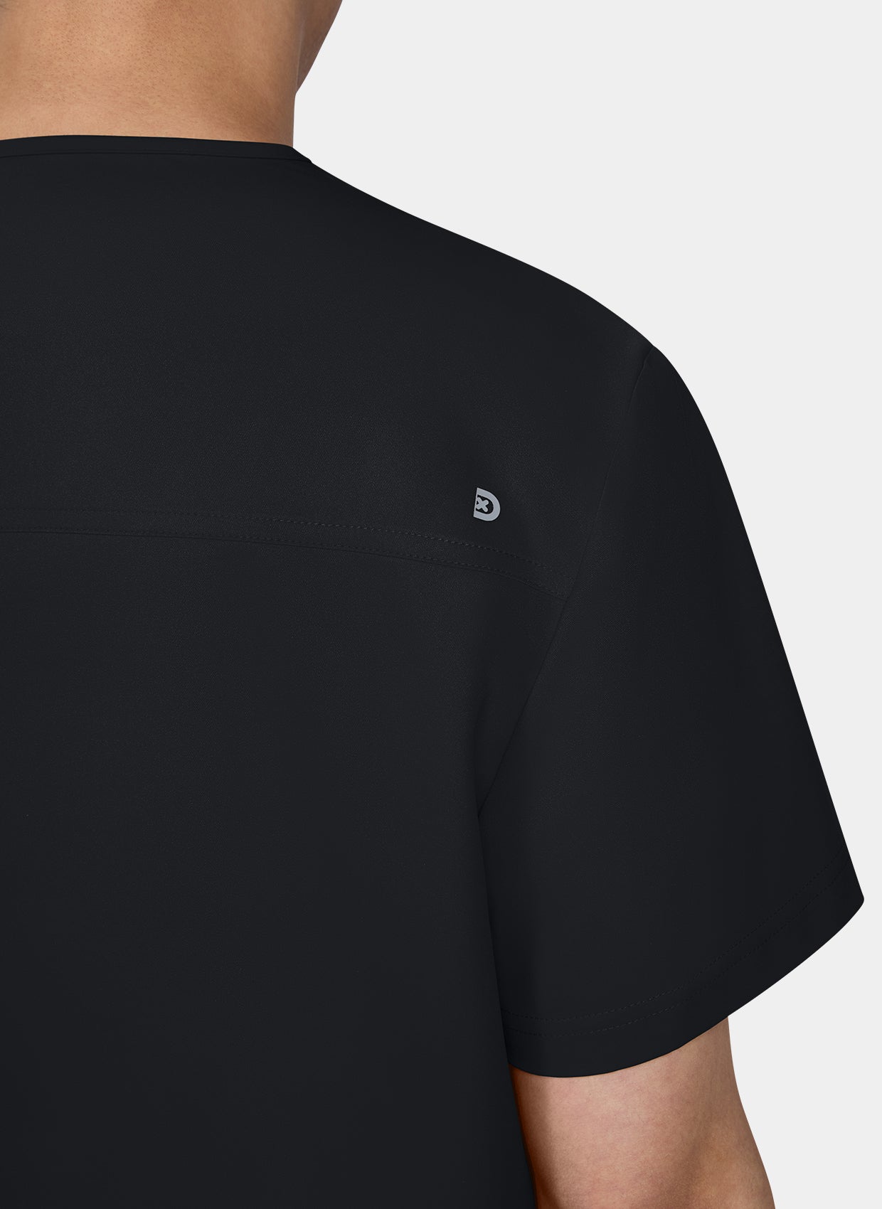 Gros plan sur l'épaule d'un homme portant une blouse médicale Koi Cureology Stasis Noir